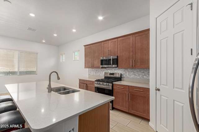 10502 W Bronco Trl, Peoria, AZ 85383 - kitchen featuring stainless steel appliances, a sink, a breakfast bar area, light countertops, and tasteful backsplash