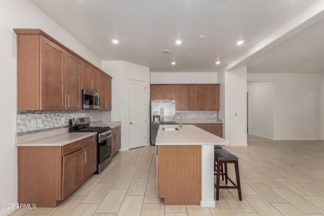 10502 W Bronco Trl, Peoria, AZ 85383 - kitchen featuring stainless steel appliances, a sink, backsplash, a kitchen breakfast bar, and a center island with sink