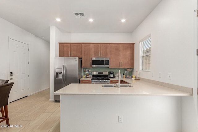 10502 W Bronco Trl, Peoria, AZ 85383 - kitchen with stainless steel appliances, a sink, light countertops, a peninsula, and brown cabinetry