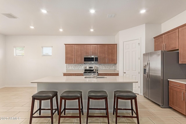 10502 W Bronco Trl, Peoria, AZ 85383 - kitchen with appliances with stainless steel finishes, a sink, a kitchen breakfast bar, decorative backsplash, and an island with sink