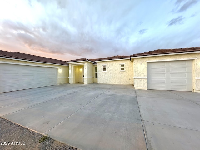 view of front of house featuring driveway, an attached garage, and stucco siding