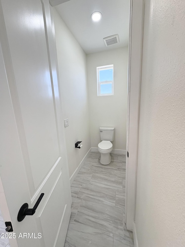 bathroom with baseboards, visible vents, and toilet