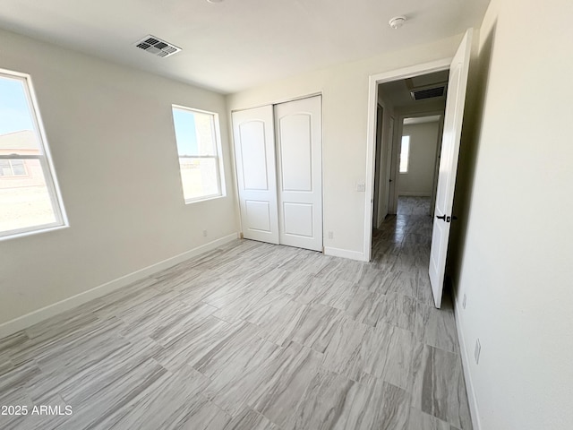 unfurnished bedroom with baseboards, visible vents, and a closet