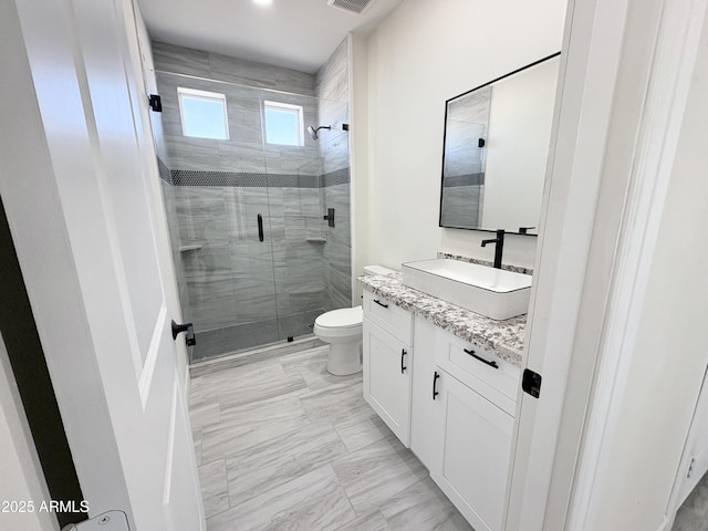 bathroom with marble finish floor, a shower stall, toilet, and vanity