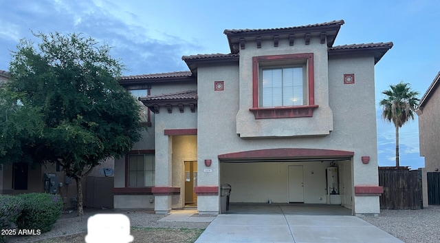 mediterranean / spanish house featuring concrete driveway, an attached garage, fence, and stucco siding