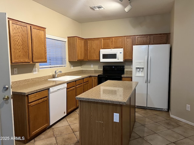 kitchen featuring white appliances, a sink, light tile patterned floors, and a kitchen island