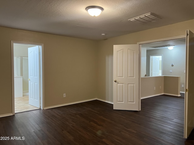 unfurnished bedroom with wood finished floors, baseboards, and connected bathroom