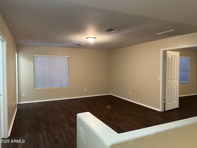 empty room featuring dark wood-type flooring and baseboards