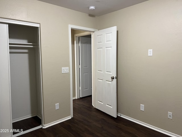 unfurnished bedroom with dark wood-type flooring, baseboards, and a closet