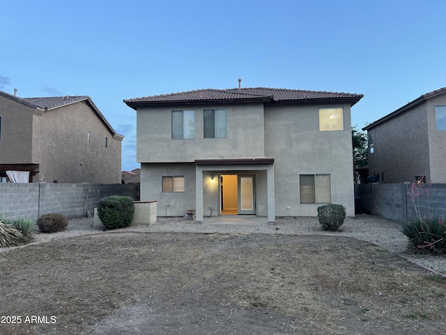 back of house with a tile roof, a fenced backyard, and stucco siding