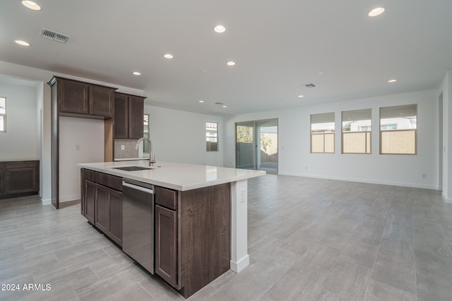 kitchen featuring dishwasher, a kitchen island with sink, sink, decorative backsplash, and dark brown cabinetry