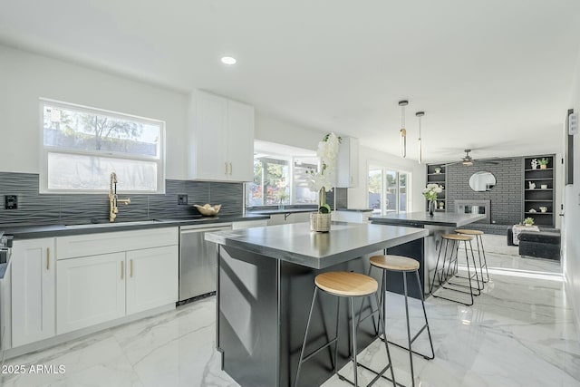 kitchen featuring sink, white cabinetry, decorative light fixtures, a center island, and dishwasher