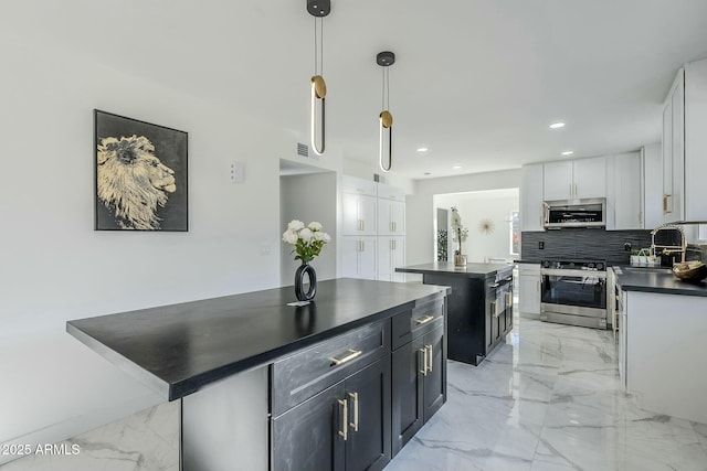 kitchen featuring pendant lighting, white cabinetry, stainless steel appliances, a kitchen island, and decorative backsplash