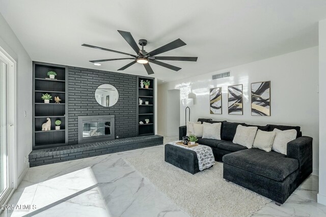 living room featuring ceiling fan, a brick fireplace, and built in features