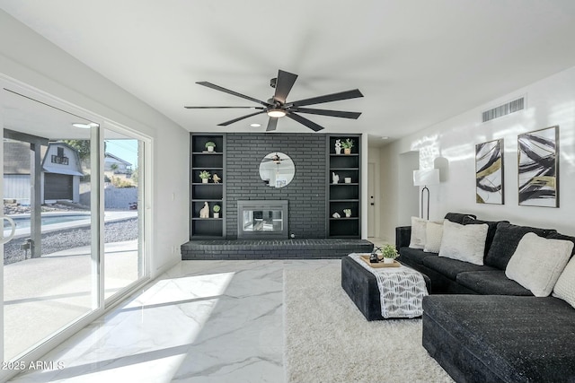 living room with built in shelves, a fireplace, and ceiling fan