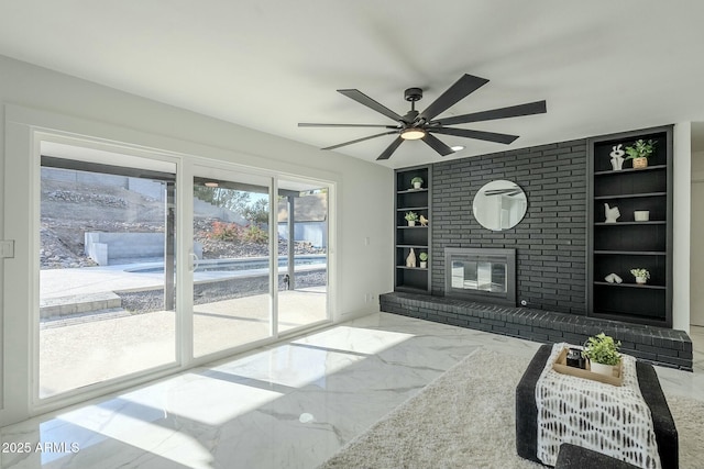 living room featuring ceiling fan, a fireplace, and built in features