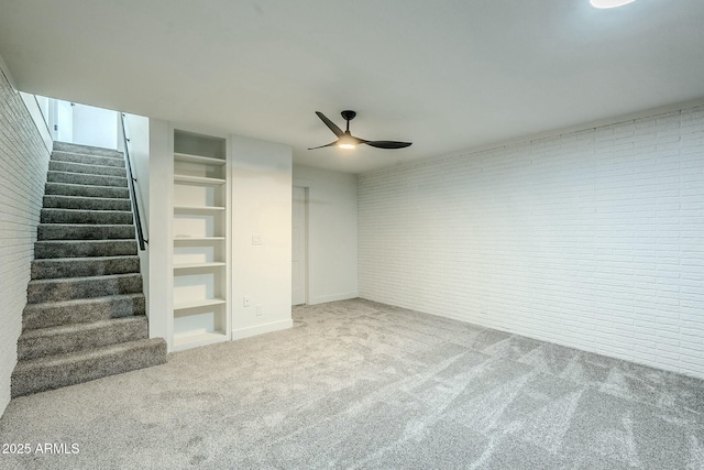 basement featuring ceiling fan, brick wall, and carpet floors