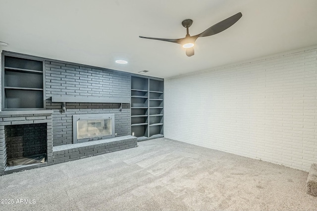 unfurnished living room with brick wall, carpet, a fireplace, and built in shelves