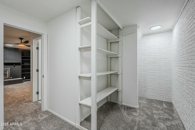 spacious closet featuring carpet flooring and a brick fireplace