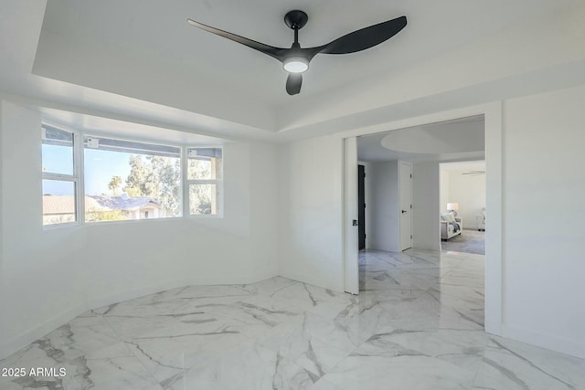 unfurnished room with ceiling fan and a raised ceiling