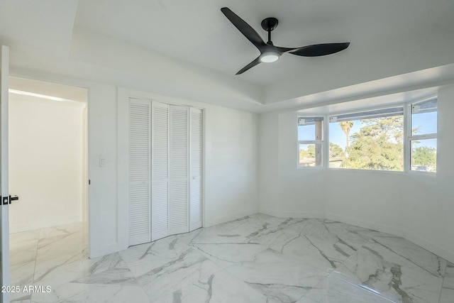 bedroom featuring a raised ceiling, ceiling fan, and a closet