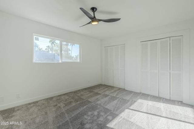 unfurnished bedroom featuring two closets, ceiling fan, and carpet flooring