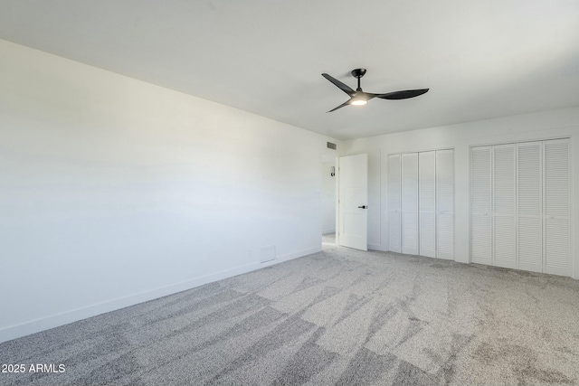 unfurnished bedroom featuring ceiling fan, multiple closets, and carpet flooring