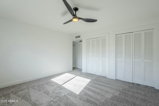 unfurnished bedroom featuring carpet flooring, two closets, and ceiling fan