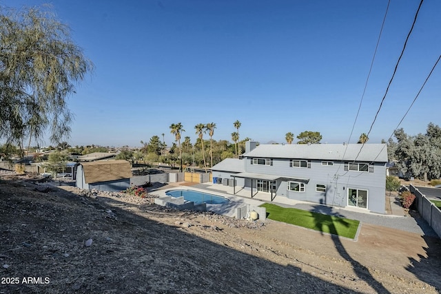 rear view of property with a fenced in pool and a patio area