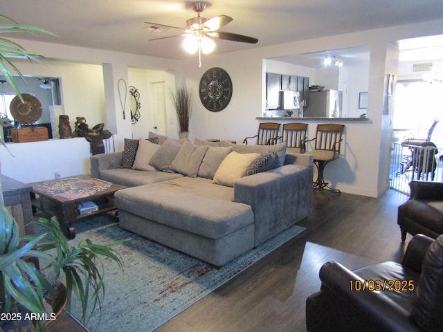 living room featuring baseboards, wood finished floors, and a ceiling fan