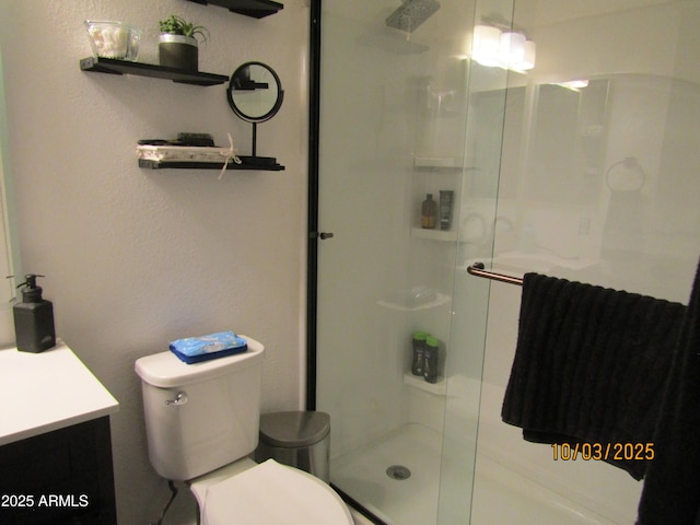 bathroom featuring a shower stall, toilet, and vanity