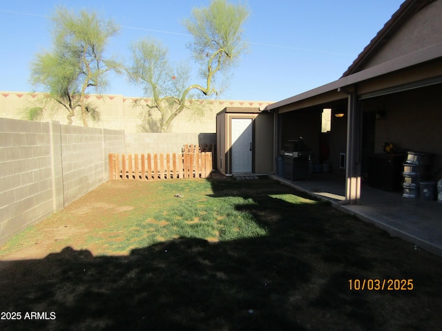 view of yard featuring a storage unit, a fenced backyard, an outdoor structure, and a patio area