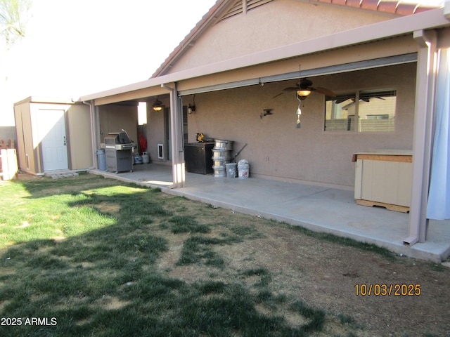 rear view of house featuring a shed, stucco siding, a patio area, an outbuilding, and a ceiling fan