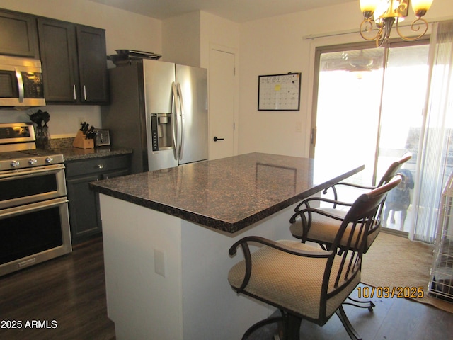 kitchen featuring a kitchen breakfast bar, a kitchen island, dark wood-style floors, stainless steel appliances, and a chandelier