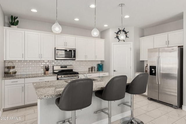 kitchen with marble finish floor, appliances with stainless steel finishes, white cabinets, and pendant lighting