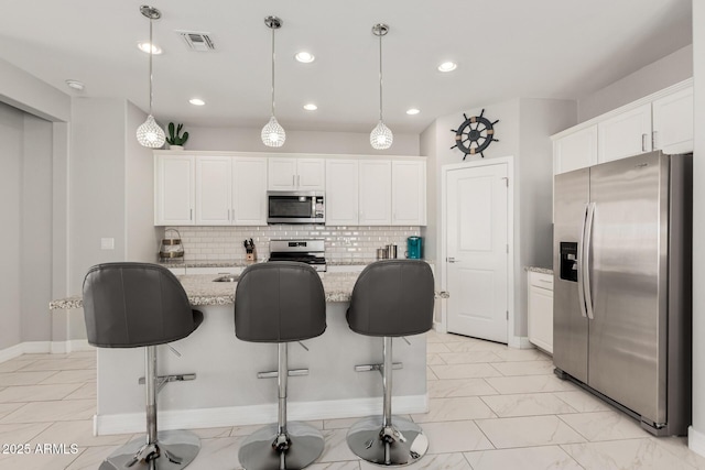 kitchen featuring visible vents, appliances with stainless steel finishes, white cabinets, and decorative backsplash