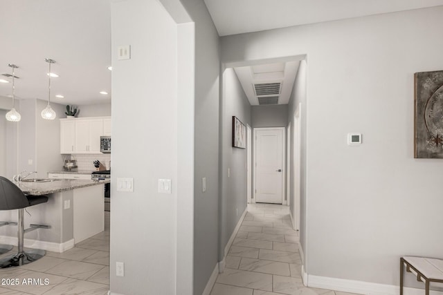 hall featuring visible vents, marble finish floor, a sink, recessed lighting, and baseboards