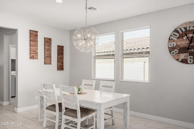 dining space featuring a notable chandelier, washer / clothes dryer, baseboards, and visible vents