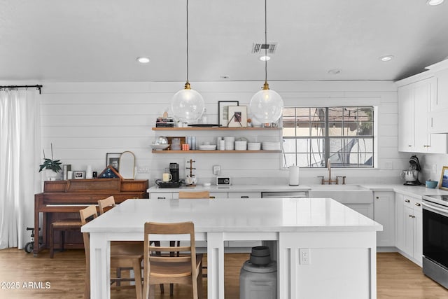 kitchen featuring white cabinets, a center island, sink, and pendant lighting