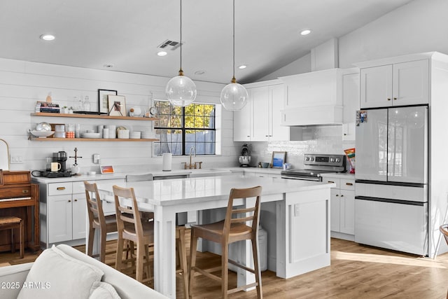 kitchen featuring a center island, sink, stainless steel appliances, lofted ceiling, and white cabinets