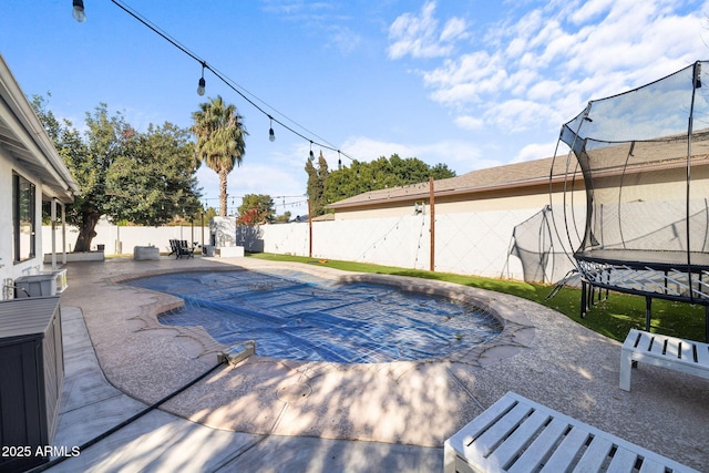 view of swimming pool featuring a trampoline and a patio