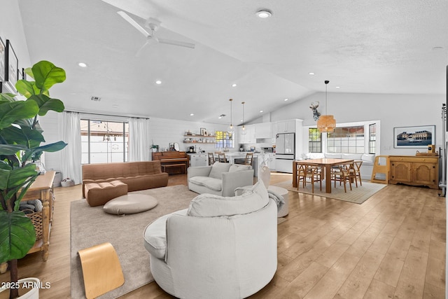 living room with ceiling fan, plenty of natural light, light hardwood / wood-style floors, and lofted ceiling