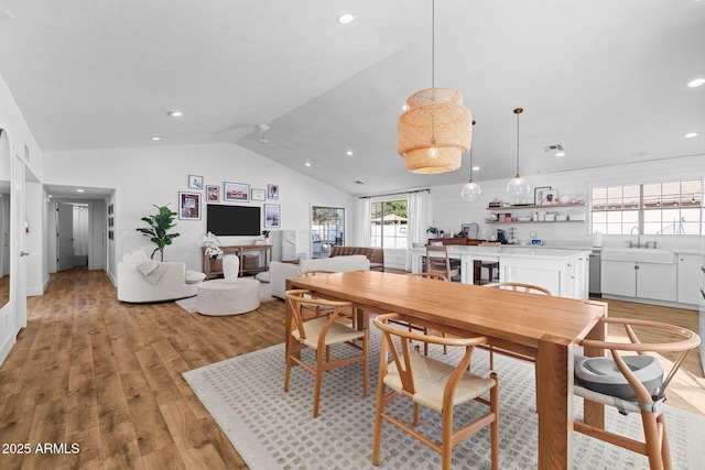 dining space with lofted ceiling, sink, and light hardwood / wood-style flooring