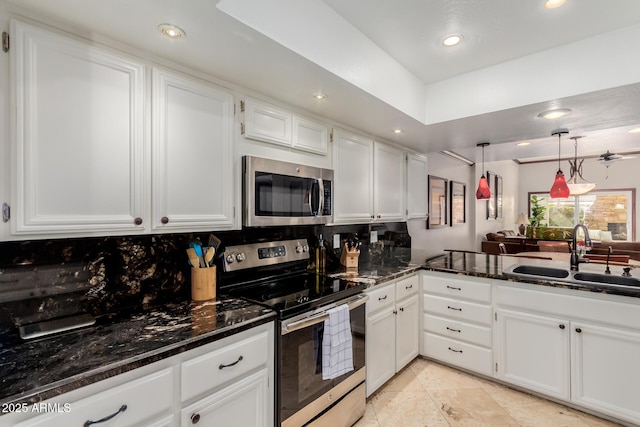 kitchen featuring sink, appliances with stainless steel finishes, white cabinetry, dark stone countertops, and tasteful backsplash