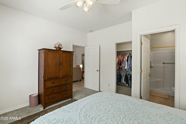 bedroom featuring a walk in closet, light colored carpet, baseboards, a closet, and ensuite bath