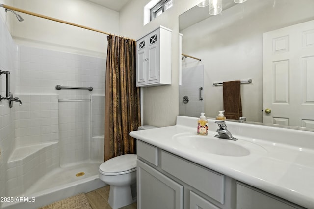 bathroom with toilet, a tile shower, and vanity