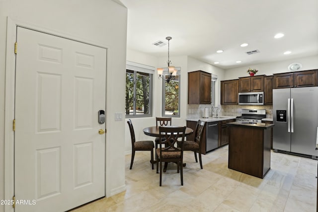 kitchen featuring dark brown cabinetry, a kitchen island, visible vents, appliances with stainless steel finishes, and a sink