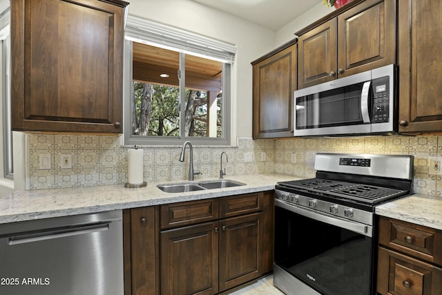 kitchen featuring light stone counters, a sink, and stainless steel appliances