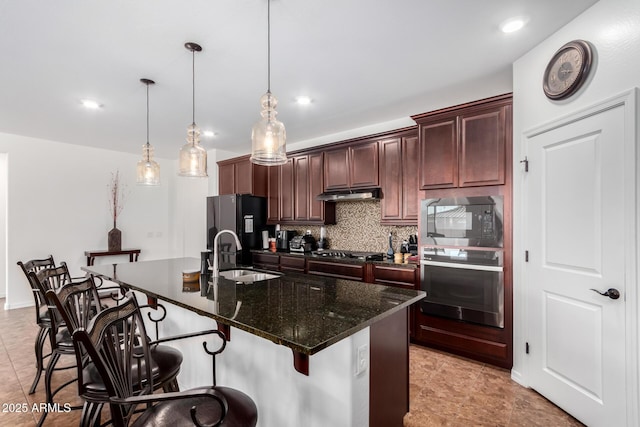 19889 W Montecito Ave, Litchfield Park, AZ 85340 - kitchen featuring black appliances, a sink, under cabinet range hood, tasteful backsplash, and a breakfast bar