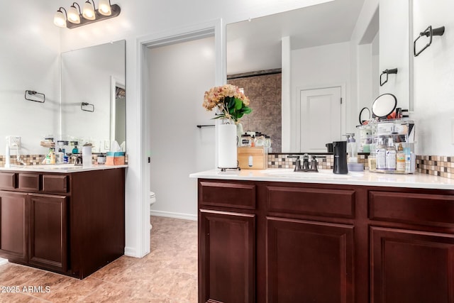 19889 W Montecito Ave, Litchfield Park, AZ 85340 - bathroom featuring two vanities, toilet, tasteful backsplash, and baseboards